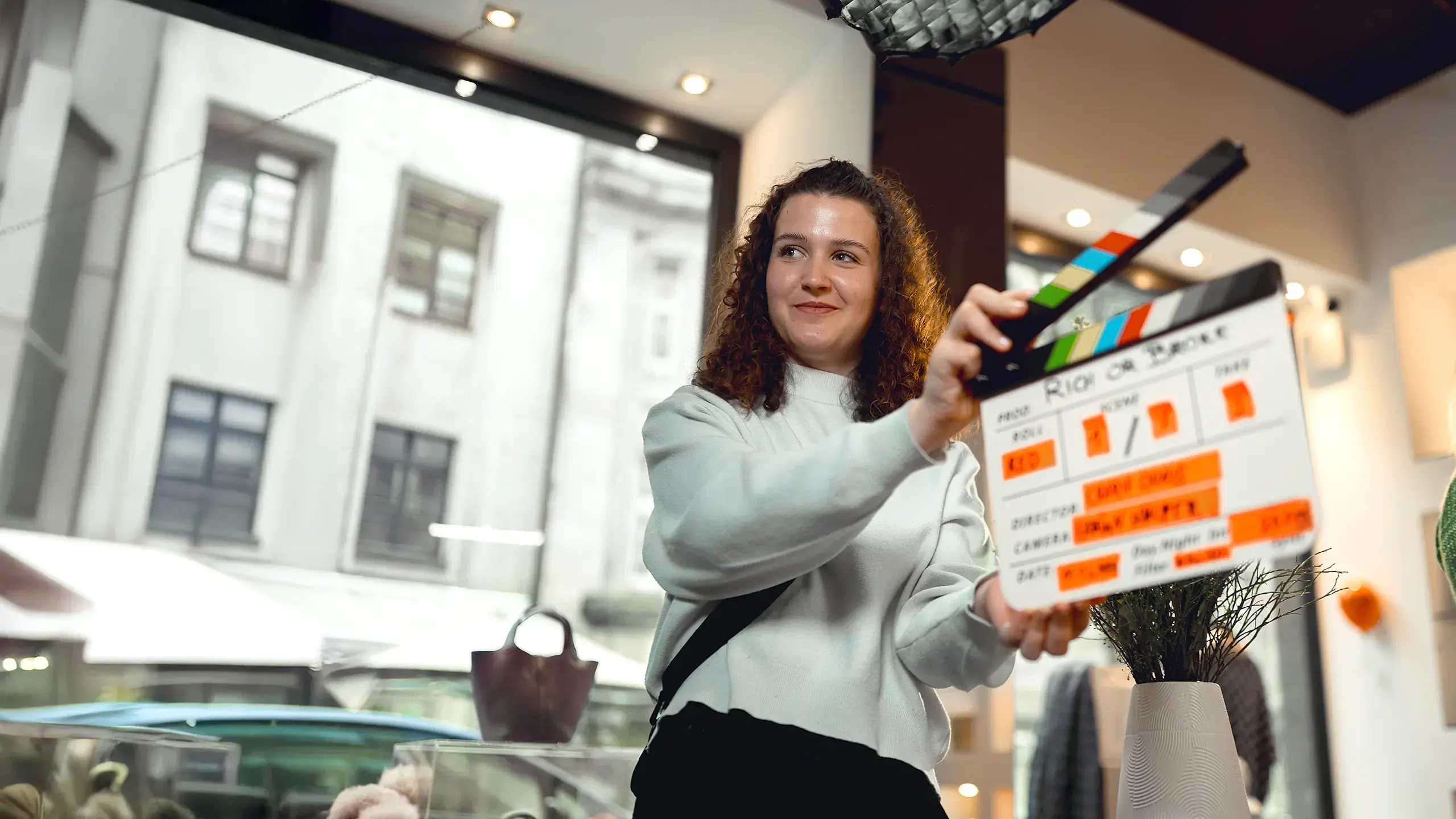 Schülerin hält eine Filmklappe während der Dreharbeiten in einem Innenraum